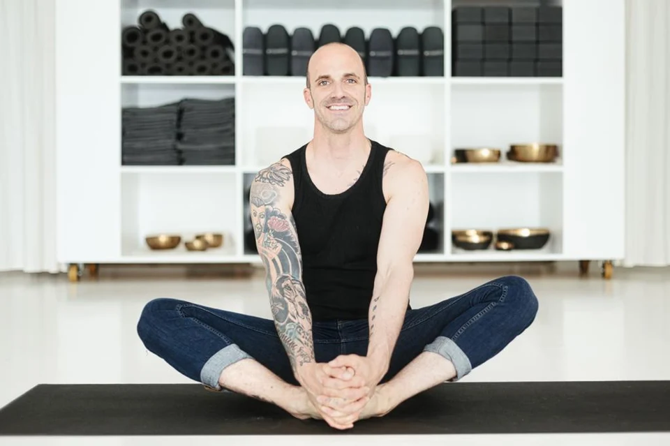 Will souriant, assis confortablement sur un tapis de yoga